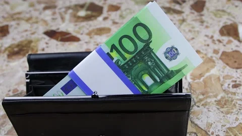 A bundle of 100 euro banknotes lies in a black wallet on a stone table, FullHD Vídeo Stock 141502337