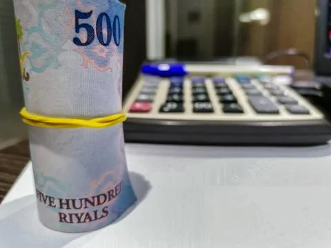 A bundle of 500 currency notes at a bank and calculator and pen in background Foto stock