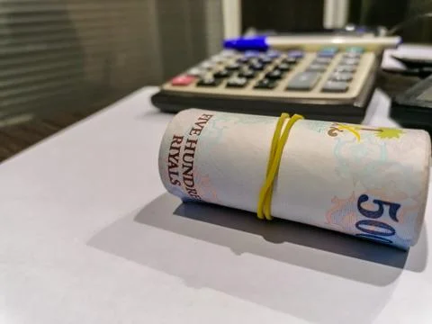 A bundle of 500 currency notes at a bank and calculator and pen in background Stock Photos