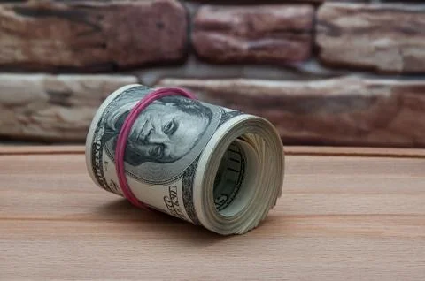 A bundle of American dollar bills of one hundred dollars on a wooden table ne Stock Photos