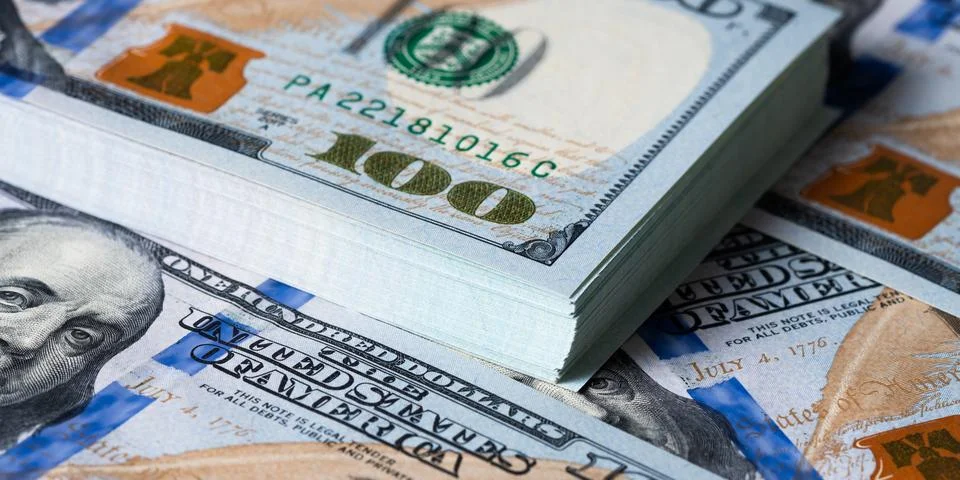 A bundle and a roll of dollars on bills of one hundred dollars. Stock Photos