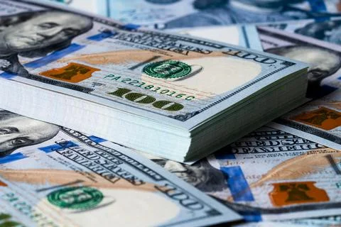 A bundle and a roll of dollars on bills of one hundred dollars. Stock Photos