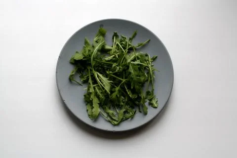Bundle of arugula on plate from above Stock Photos