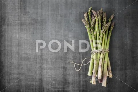 A bundle of asparagus on a grey surface Stock Photos