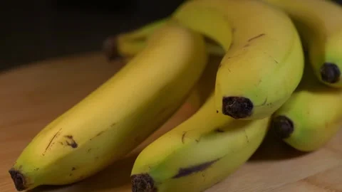 Bundle of banana's spinning on bamboo cutting board Stock Footage 264083923