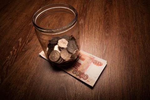 Bundle of bank notes and a glass jar with coins Foto stock