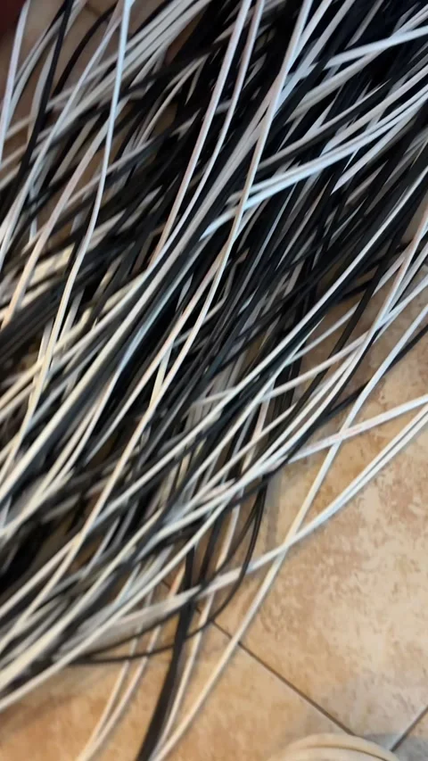 Bundle of black and white electrical wires lying on a tiled floor. Energy cables Stock Footage 339432611