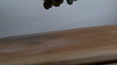 Bundle of black grapes falling onto a cutting board in slow motion Stock Footage 100008387