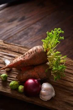 Bundle of carrots with soil over rustic wooden background, side view, close-up Stock Photos