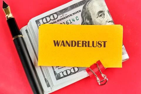 A bundle of cash stacked with a yellow note labeled wanderlust and an elega.. Foto stock