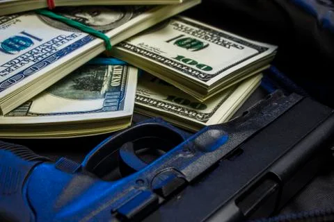 Bundle of dollars with a gun in a black bag Stock Photos