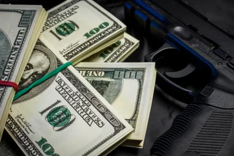 Bundle of dollars with a gun in a black bag Stock Photos