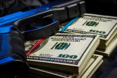 Bundle of dollars with a gun in a black bag Stock Photos