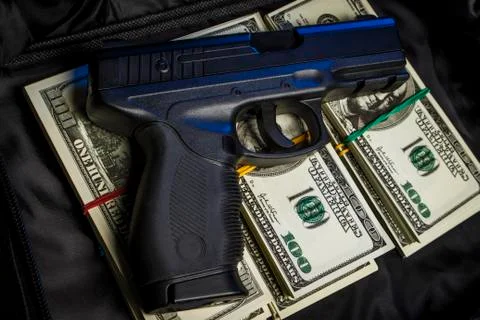 Bundle of dollars with a gun in a black bag Stock Photos