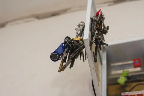 A bundle of door keys hangs from a small metal door. Random keys to front doo Stock Photos