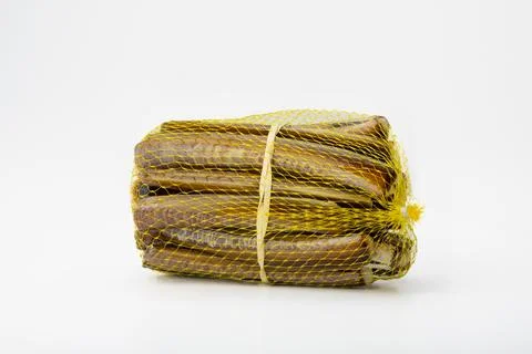 Bundle of dried pollack fish in a yellow net on white background Foto stock