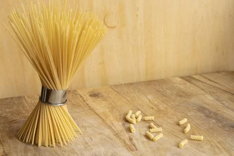 Bundle of dry spaghetti and fusilli pasta on wooden background Stock Photos