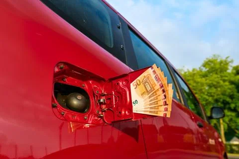 Bundle of fifty euro notes sticking out of a car's open fuel tank filler cap Stock Photos