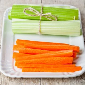 Bundle of fresh green celery stems and carrot in plate Stock Photos