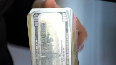 A bundle of money on the table, a lot of dollars in their hands, business people Stock Footage 100371976