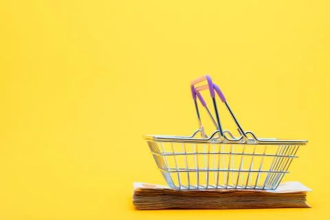 On a bundle of notes lies an empty grocery basket with raised handles Stock Photos