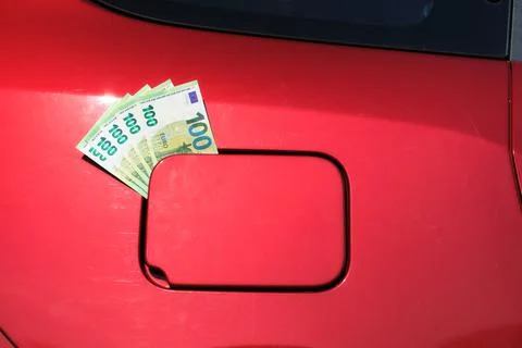 Bundle of one hundred euro notes sticking out of a fuel tank lid Foto stock
