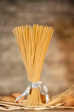 Bundle of pasta standing on a table with wheat and eggs Stock Photos
