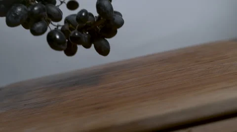 Bundle of purple grapes falling and rolling onto a cutting board in slow motion Stock Footage 64591157