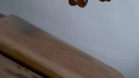 Bundle of purple grapes falling and rolling onto a cutting board in slow motion Stock Footage 100008237