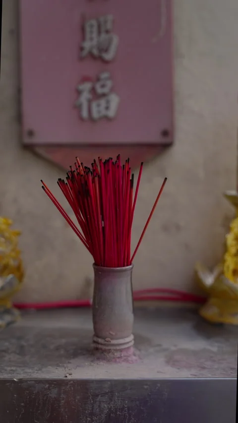 A bundle of red incense sticks standing upright in a weathered ceramic holder Video stock 312204011