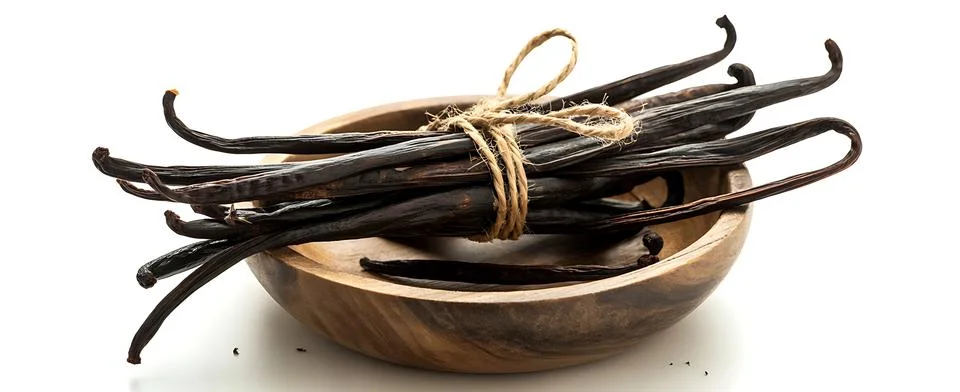 A bundle of vanilla beans in a dark, rustic wooden bowl, isolated on a whit.. Stock Photos