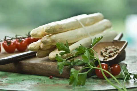 A bundle of white asparagus on a chopping board with a knife, peppercorns, Stock Photos