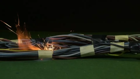A bundle of wires lies on the surface, and a bright short circuit with sparks oc Stock Footage 323143218