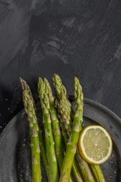 Bundle of young raw uncooked organic green asparagus with sliced lemon Stock Photos