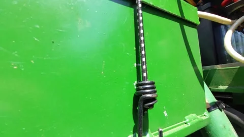 Bungee cord with black hook securing a green metal battery box or machinery comp Stock Footage 336482692