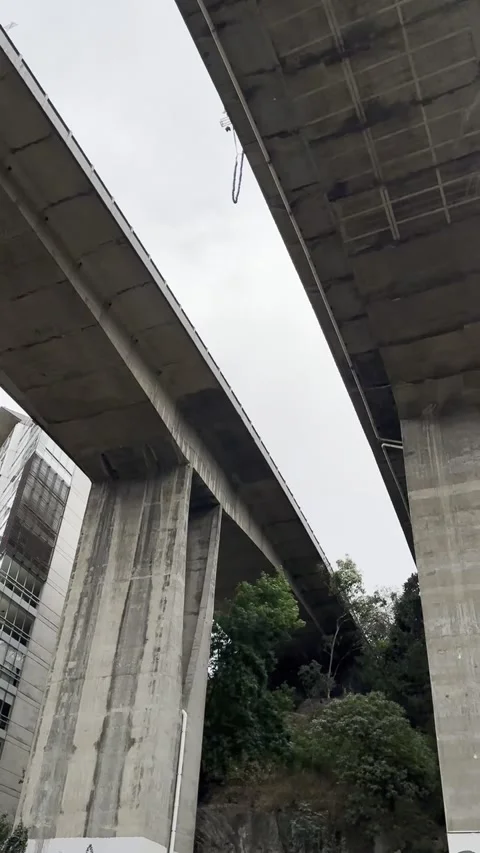A bungee jumper leaps from in between two bridges in Mexico City Stock Footage 345670252