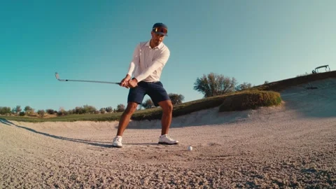 Bunker shot exploding sand as golfer blasts out of a desert trap in slow motion Stockbeeldmateriaal 340117571