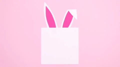 Bunny ears appear under paper card note. Easter stop motion flat lay Stock Footage 149916482
