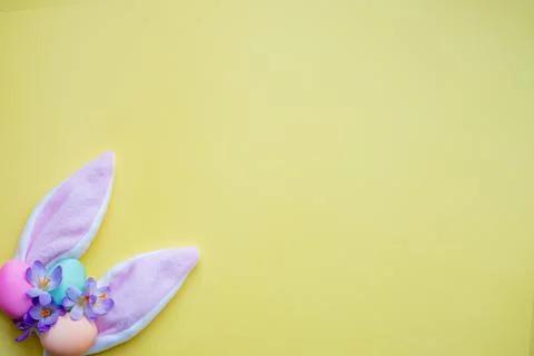Bunny ears, easter eggs and spring flowers on yellow background. simple Stock Photos