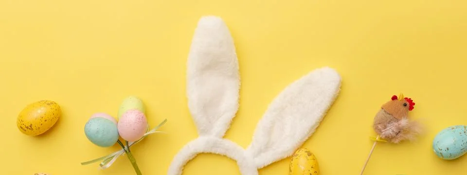 Bunny rabbit ears and Easter decor on yellow background. Easter minimal Stock Photos