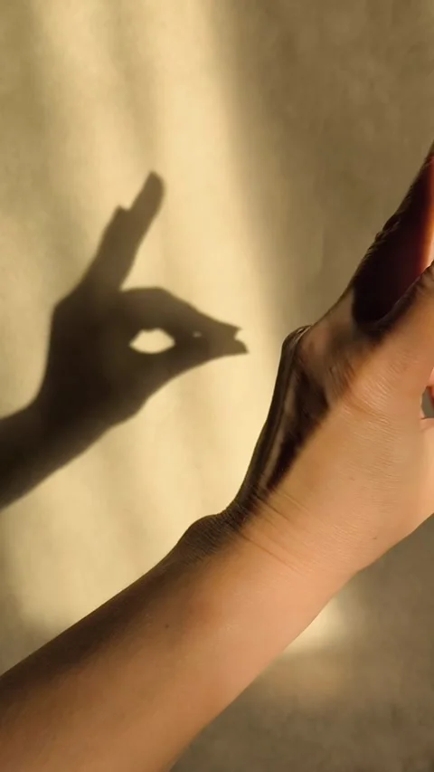 Bunny-shaped shadow on the wall from sunlight. The woman holds her fingers in Stock Footage 326122820
