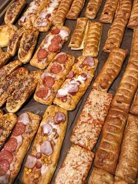 Buns containing sausages and corn displayed alongside sausages in dough, sh.. Stock Photos