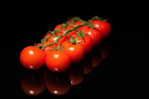 Bunsh of nice, small, red tomatoes on the black bachground Stock Photos