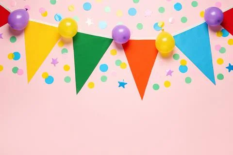 Bunting with colorful triangular flags and other festive decor on pink backgr Stock Photos