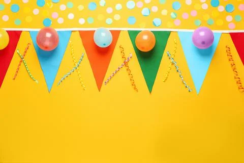 Bunting with colorful triangular flags and other festive decor on yellow back Stock Photos
