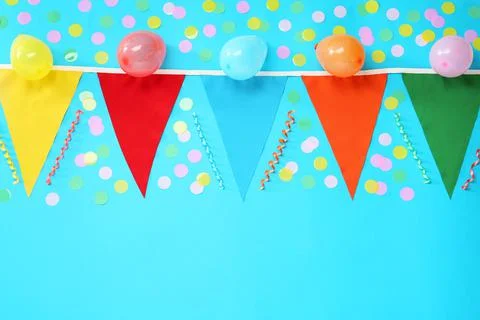 Bunting with colorful triangular flags, balloons, streamers and confetti on l Stock Photos