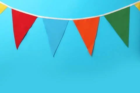 Bunting with colorful triangular flags on light blue background. Space for te 写真素材
