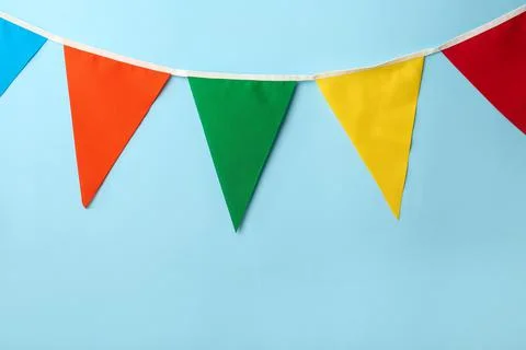 Bunting with colorful triangular flags on light blue background Stock Photos