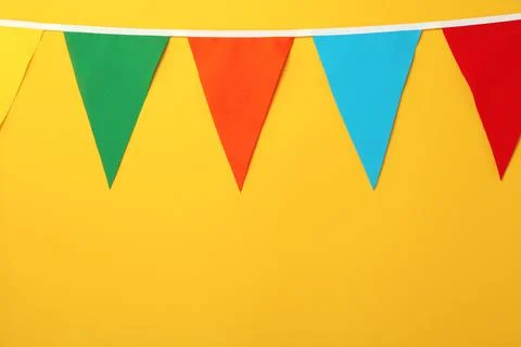 Bunting with colorful triangular flags on orange background, space for text Stock Photos