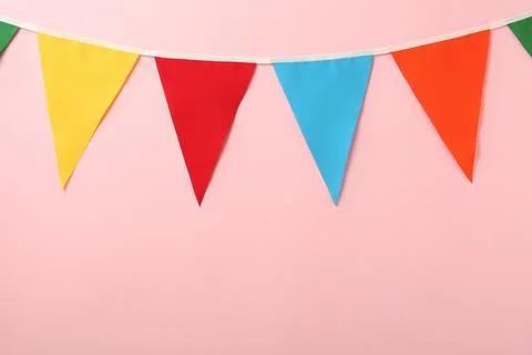 Bunting with colorful triangular flags on pink background. Space for text Stock Photos